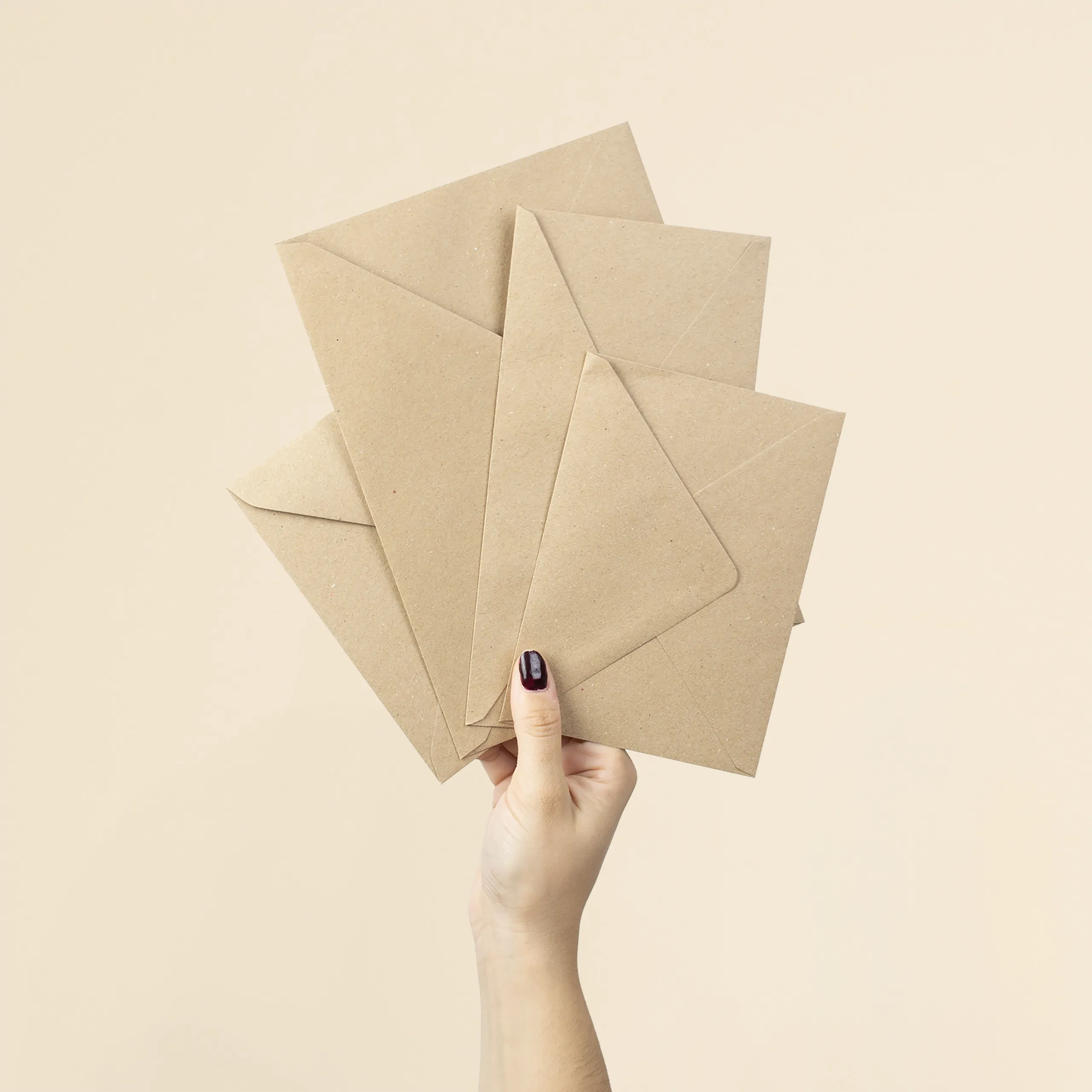 Mano sujetando cuatro sobres kraft de diferentes tamaños
