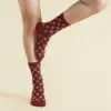 Piernas con calcetines rojos personalizados con logo sobre un fondo beige
