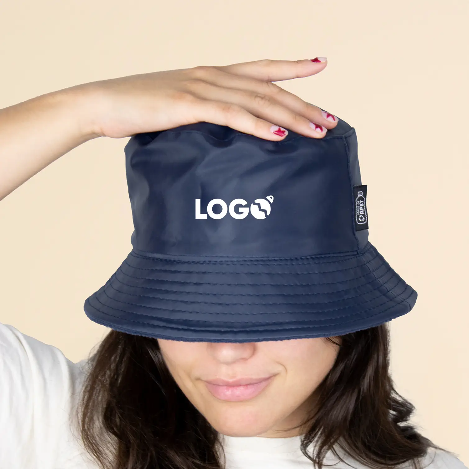 Chica con un gorro azul impermeable reversible ecológico sobre un fondo beige